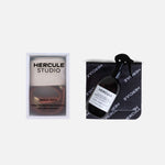 Sangle de transport dans sa boite de rangement et spray parfumé avec son tissu microfibre de la marque Hercule Studio photo packshot fond blanc
